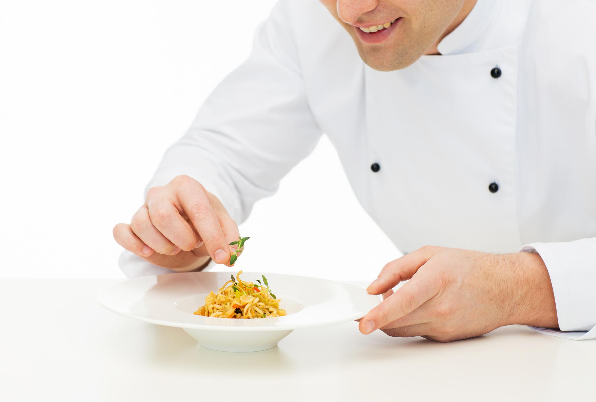 Chef arranging plated dish on wooden table